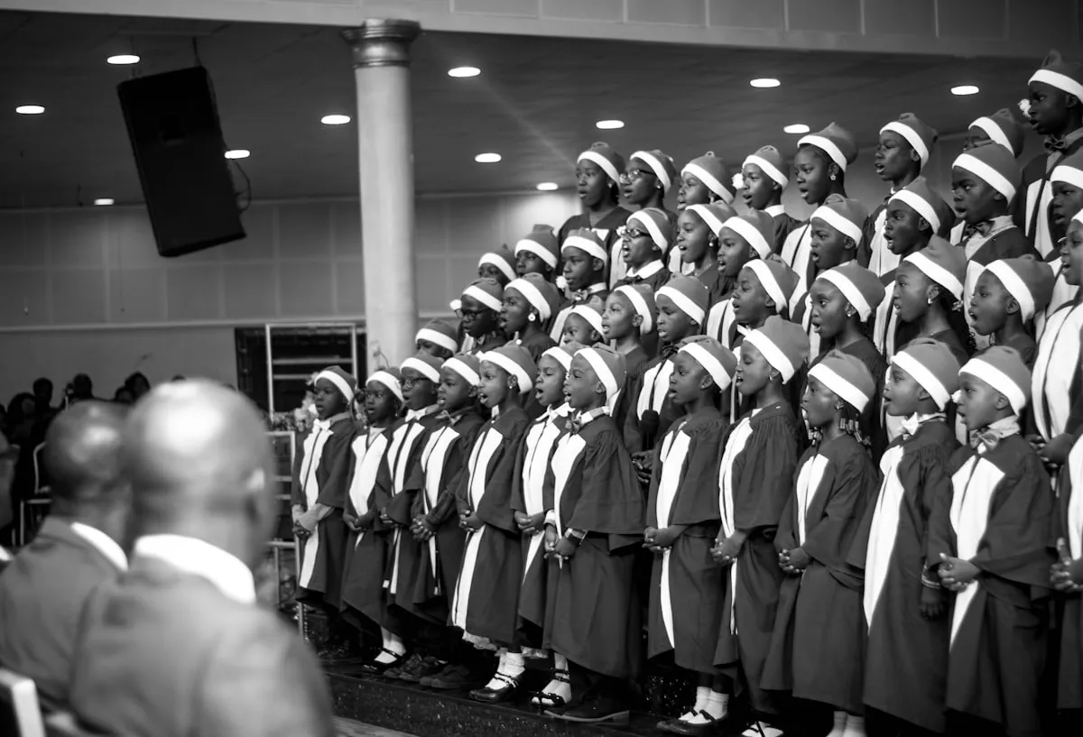 Coro infantil cantando junto, con vestuario formal, sobre un escenario