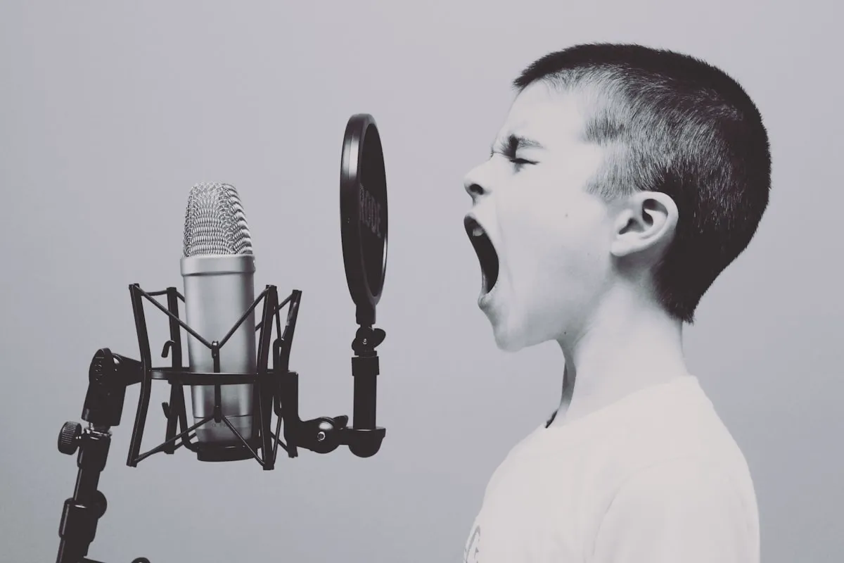 Niño cantando frente a un micrófono durante la preparación vocal